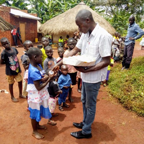 JDI staff giving plastic bottles to children in Olyeko Ambe village, Papoga Parish to pick their stool sample for examination during deworming campaign.