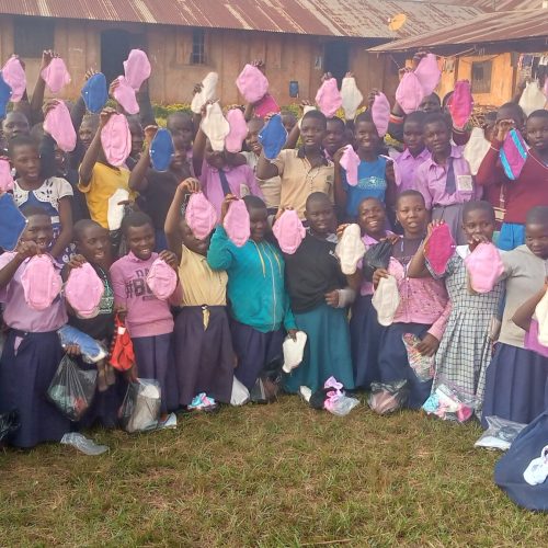 School girls showing their reusable pads that they have received from JDI Organization.